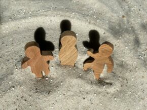 Drei Holzfiguren im Sand